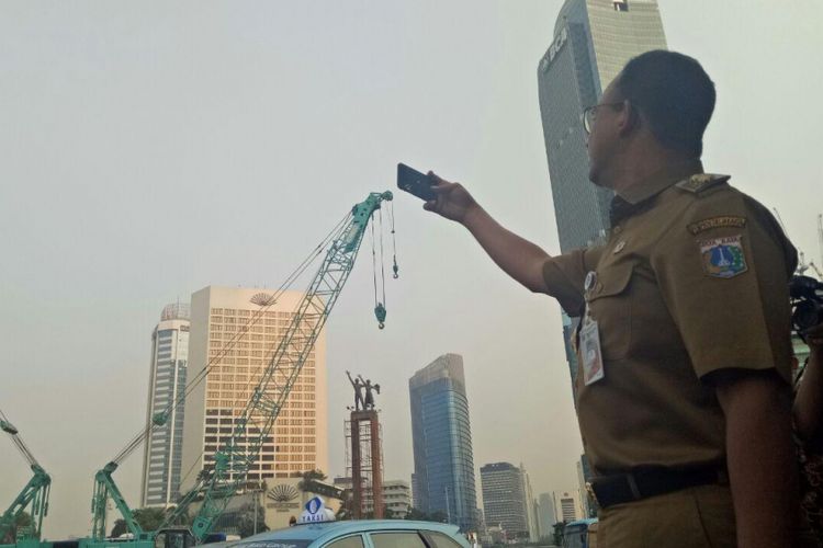Gubernur DKI Jakarta Anies Baswedan memotret Patung Selamat Datang di Bundaran HI setelah jembatan penyeberangan orang (JPO) dibongkar, Selasa (31/7/2018).