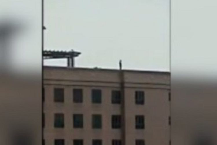 Tangkapan layar video yang memperlihatkan seseorang berdiri di atap seolah hendak bunuh diri.