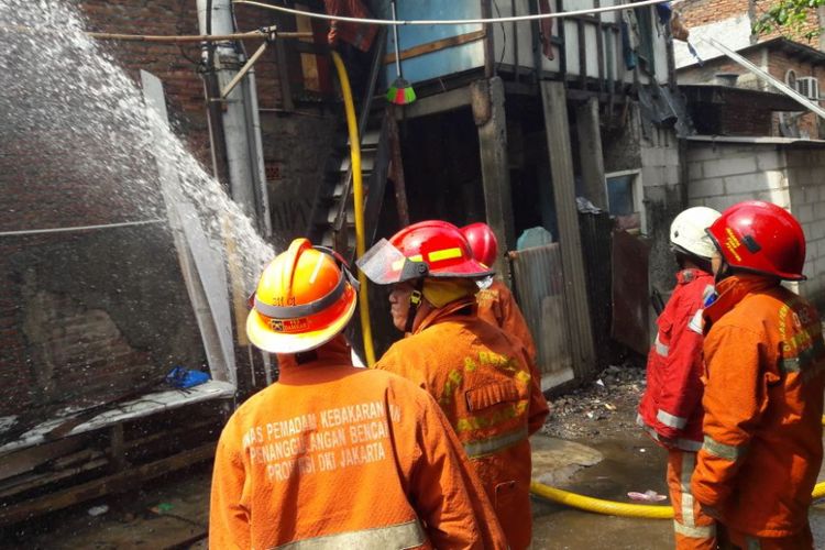 Petugas pemadam kebakaran berusaha memadamkan api yang melalap sebuah rumah kontrakkan di Penjaringan, Rabu (7/3/2018)