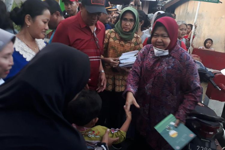 Wali Kota Surabaya Tri Rismaharini membagikan sejumlah buku kepada anak-anak usai meninjau lokasi kebakaran yang menghanguskan 16 rumah di Kelurahan Gundih, Kecamatan Bubutan, Surabaya, Rabu (10/7/2019).