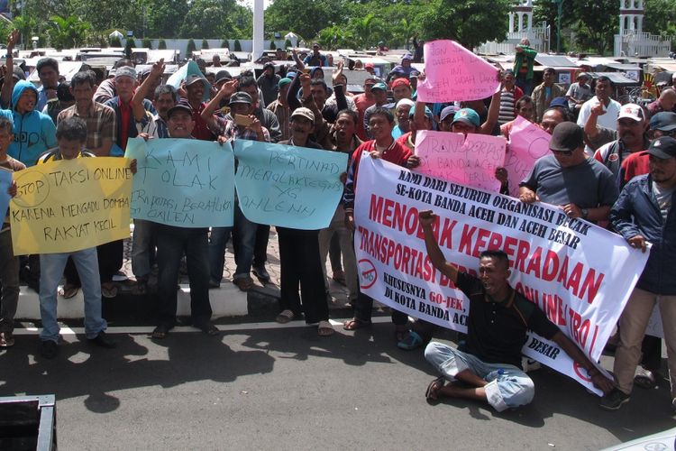 Ratusan pekerja angkutan umum di Banda Aceh melakukan aksi protes di Kantor Gubernur Aceh, Senin (16/10/2017). Mereka meminta Gubernur Aceh Irwandi Yusuf mengeluarkan perintah menghentikan aktiVitas angkutan umum berbasis online karena menurunkan pendapatan para sopir angkutan umum lainnya.