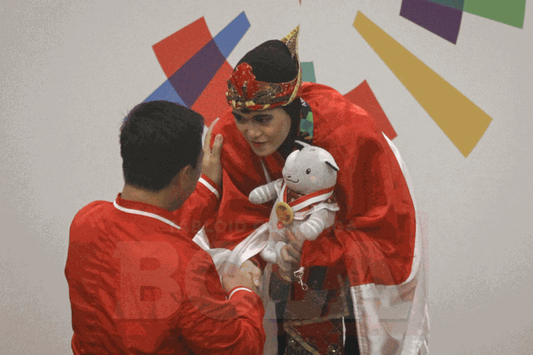 Atlet pencak silat Puspa Arumsari dikalungi medali oleh Menpora Imam Nahrawi seusai meraih medali emas Asian Games 2018, 27 Agustus 2018. 