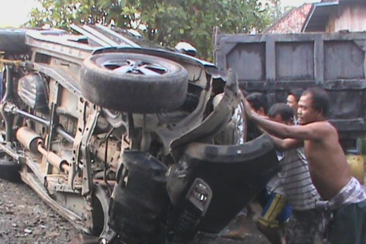 Warga beramai-ramai mengembalikan posisi kendaraan Toyota Rush yang terbalik ke posisi semula. Akibat kecelakaan ini, satu orang terluka dan dilarikan ke rumah sakit.