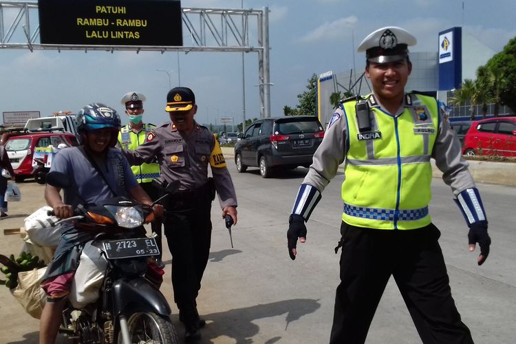 Petugas kepolisian dari Polres Malang saat mengarahkan pengendara motor yang terlanjur masuk akses Tol Pandaan-Malang, Sabtu (1/6/2019)
