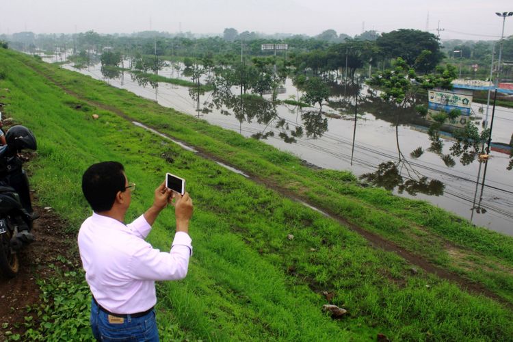 Sejumlah warga mengabadikam moment jalan raya porong yang terendam banjir di atas tanggul lumupr lapindo Porong, Sidoarjo, Jawa Timur, Selasa (28/11/2017). Banjir yang membuat Jalan Raya Porong serta Rel Kereta Api Jalur Timur lumpuh itu, meluas dan naik dari ketinggian 55 cm menjadi 86 cm di atas permukaan rel.