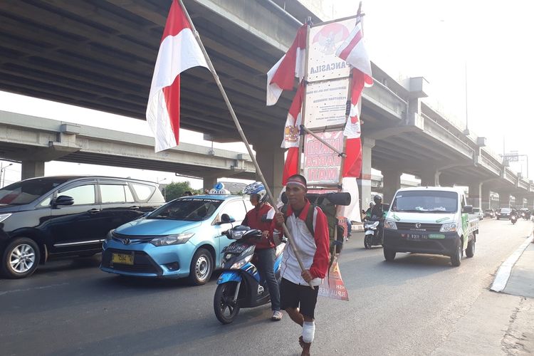 Watimin (36) pria asal Cilacap, Jawa Tengah yang melakukan aksi jalan kaki keliling Indonesia sedang berjalan di Jalan Irigasi Kalimalang, Duren Sawit, Jakarta Timur, Jumat (6/9/2019).
