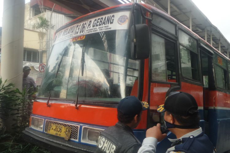  Petugas dari Suku Dinas Perhubungan Jakarta Timur menderek sebuah metromini jurusan Kampung Melayu-Pulogebang yang melintas di jalur busway di Jalan Bekasi Barat, Jakarta Timur. Sopir tersebut marah-marah karena tak terima bus yang dia kendarai diderek petugas, Rabu  (2/8/2017)