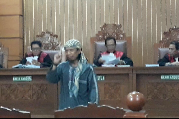 Terdakwa kasus terorisme Aman Abdurrahman tersenyum dan mengangkat satu jarinya seusai membacakan nota pembelaan atau pleidoi dalam persidangan di Pengadilan Negeri Jakarta Selatan, Jumat (25/5/2018).