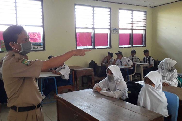 Murid dan guru SMPN 21 Kota Tangerang yang menutup wajahnya dengan masker saat pelajaran dimulai pada Senin (15/07/2019).