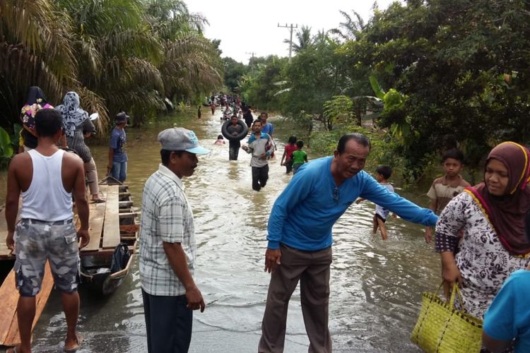 Banjir melanda jalan penghubung Desa Pulau Birandang dan Desa Karangan Tinggi, Kecamatan Kampar Timur, Kabupaten Kampar, Riau, Minggu (9/12/2018). Warga sedang mengarungi banjir dan sepeda motor diseberangkan dengan menggunakan rakit.