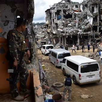 Militer terlihat tengah melihat kedatangan para jurnalis saat tiba di kota Marawi yang hancur setelah ISIS. (AFP/Ted Aljibe)