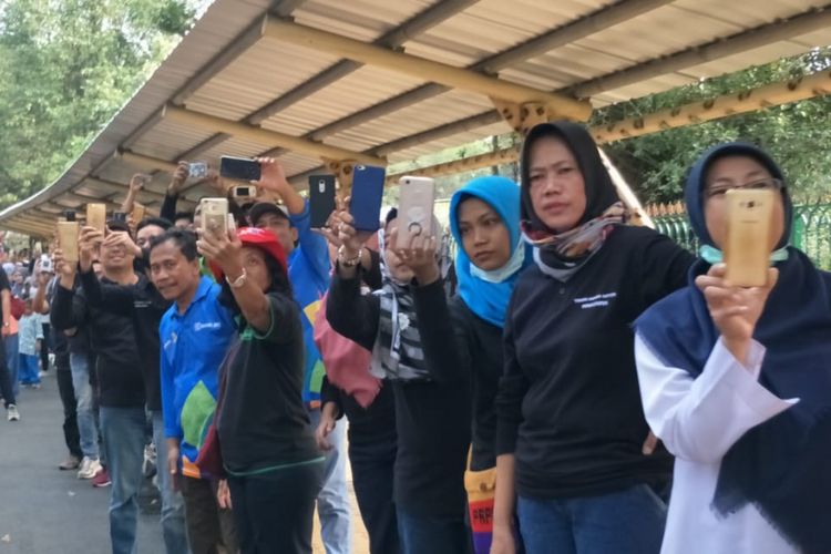 Warga menyorot jalannya prosesi torch relay atau pawai obor Asian Games di Taman Margasatwa Ragunan, Jakarta Selatan, Rabu (15/8/2018).
