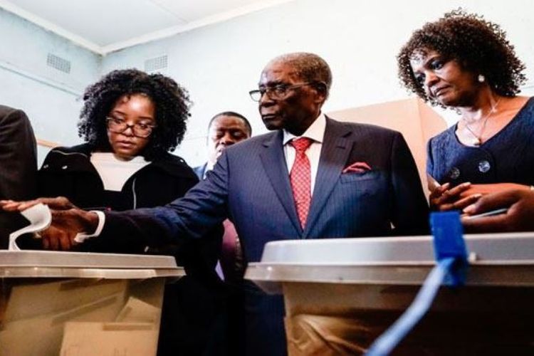 Mantan presiden Zimbabwe Robert Mugabe (tengah) memasukkan surat suara dengan didampingi istrinya Grace dan putrinya Bona.