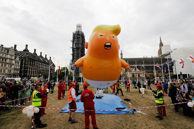 Peserta unjuk rasa menyiapkan balon Bayi Trump sebelum aksi unjuk rasa di Alun-alun Parlemen Inggris, Selasa (4/6/2019).