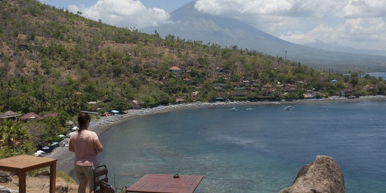 Seorang wisatawan menikmati pemandangan di Pantai Desa Amed, Karangasem, Bali, Jumat (29/9/2017). Kementerian Pariwisata menyatakan, secara umum pariwisata Bali masih normal meskipun terjadi peningkatan aktivitas Gunung Agung yang saat ini pada level awas.