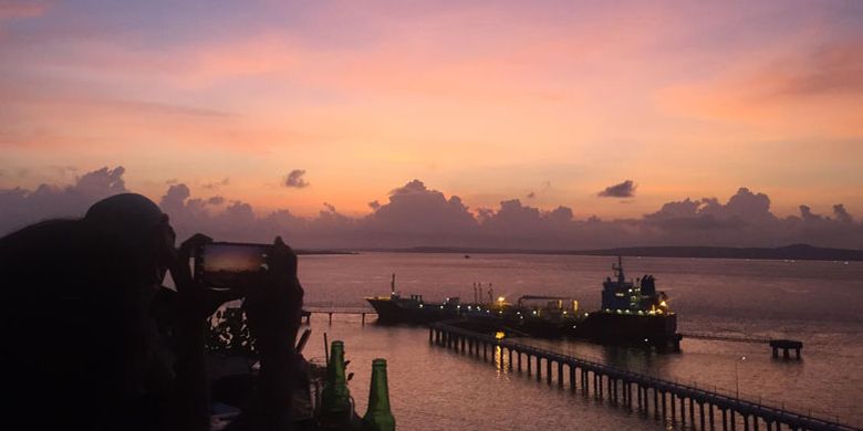 Wisatawan menikmati panorama matahari terbenam di Tebing Kafe & Bar di Kecamatan Alak, Kota Kupang, Nusa Tenggara Timur, Minggu (9/12/2018). Pemandangan matahari terbenam yang dilengkapi dengan lanskap Pelabuhan Tenau bisa jadi salah satu pilihan tempat untuk menikmati matahari terbenam.