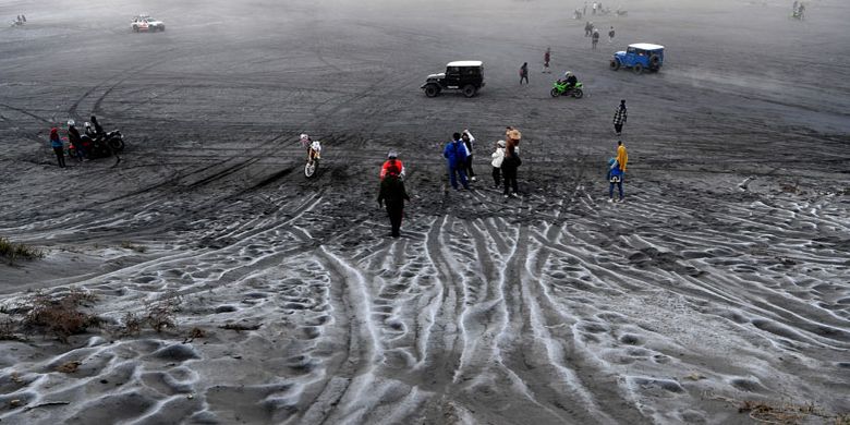 Pengunjung melintas di hamparan pasir yang diselimuti empun upas di kawasan Gunung Bromo, Probolinggo, Jawa Timur, Minggu (30/6/2019). Fenomena embun upas tersebut disebabkan penurunan suhu yang mencapai 0 derajat celcius pada malam hari.