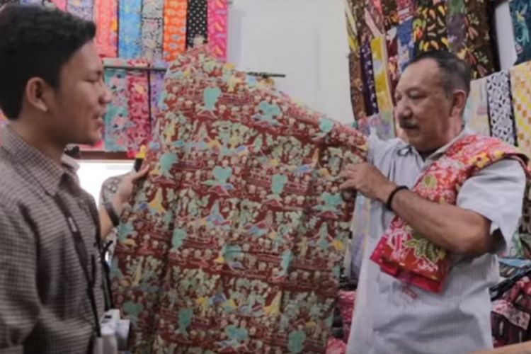 Tri Utomo, pemilik Omah Batik Ngesti Pandowo sedang membedakan batik buatan tangan asli dengan kain tekstil yang hanya dicetak bergambar batik di gerainya, Jumat (16/6/2017).