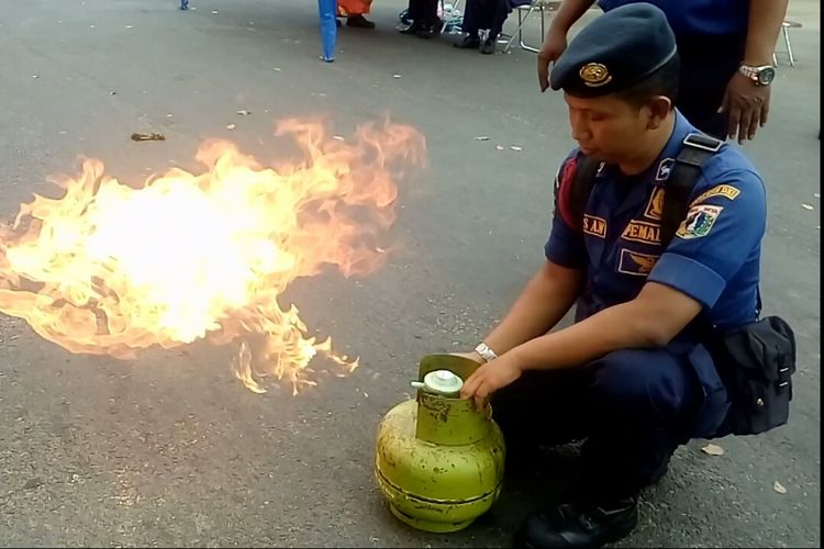 Petugas Sudin Damkar Jakarta Utara memperagakan cara mengatasi api akibat kebocoran regulator tabung gas hanya dengan jari, Minggu (20/8/2017).