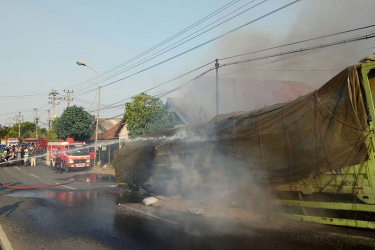 Petugas berusaha memadamkan api yang membakar truk tronton AG 8421 US,  akibat mengalami pecah ban di Jalur Pantura Demak KM 13,5 , Desa Loireng,  Kecamatan Sayung,  Demak,  Senin (18/9/2017) sore
