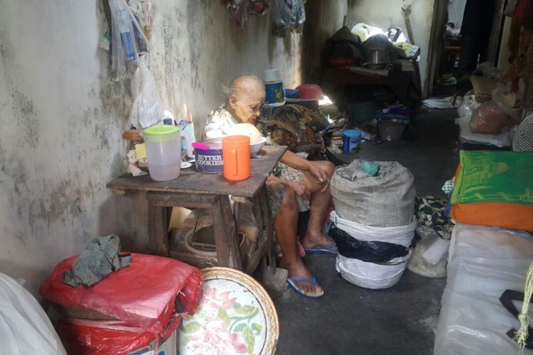 Nenek Warti membungkus barang-barang untuk dipersiapkan dijual di lapaknya di Jalan Trunojoyo, Kota Madiun, Jawa Timur. 