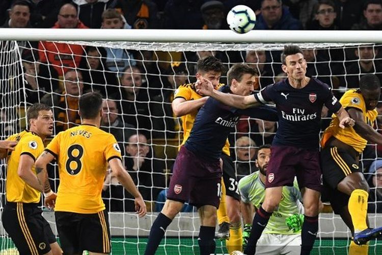 Bek Arsenal Nacho Monreal dan Laurent Koscielny berebut bola dengan gelandang Wolverhampton Wanderers Leander Dendoncker pada laga pekan ke-35 Liga Inggris di Stadion Molineux, 24 April 2019.