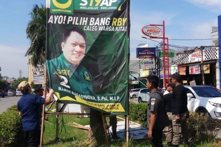 Nampak petugas menurunkan Alat Peraga Kampanye (APK) Pemilu 2019 di jalanan protokol Kota Bekasi, Senin (15/4/2019). 
