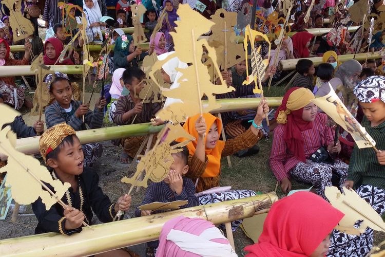 Ratusan anak ikut menarikan wayang kertas ketika menyaksikan dalang cilik Kevin Rabbani beraksi di panggung wayang di Balai Desa Tayuban, Panjatan, Kulon Progo, DI Yogyakarta. Wayang kertas di tangan anak-anak itu jadi seperti mainan yang menyenangkan mereka.