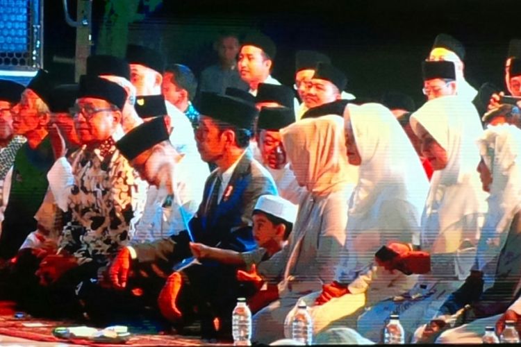 Presiden Jokowi duduk berdampingan dengan cucunya Jan Ethes Srinarendra dalam Apel Akbar Santri Nusantara peringatan Hari Santri Nasional 2018 di Benteng Vastenburg Solo, Jawa Tengah, Sabtu (20/10/2018) malam.