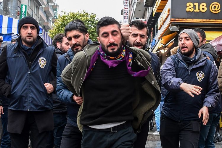 Polisi anti-huru hara Turki menahan salah seorang peserta dalam aksi protes di Istanbul, Minggu (21/1/2018).