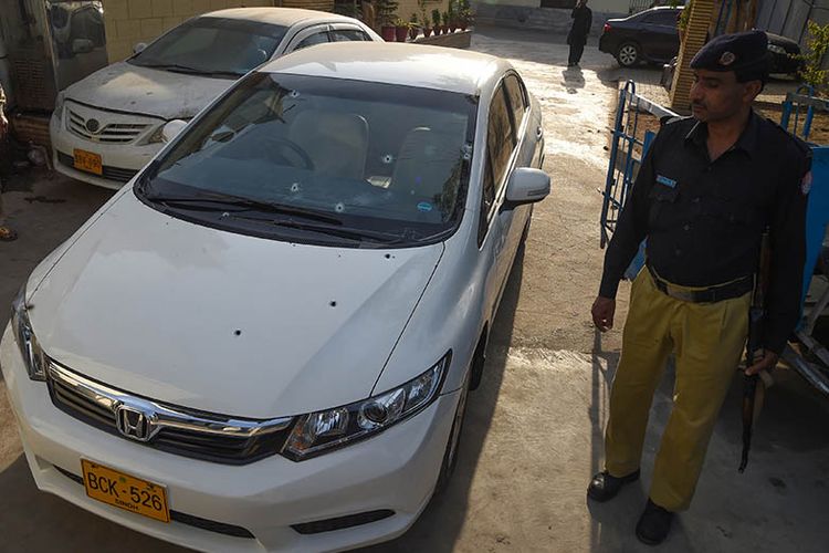 Polisi Pakistan berjaga di samping mobil yang ditumpangi warga China korban penembakan di Karachi, Senin (5/2/2018).
