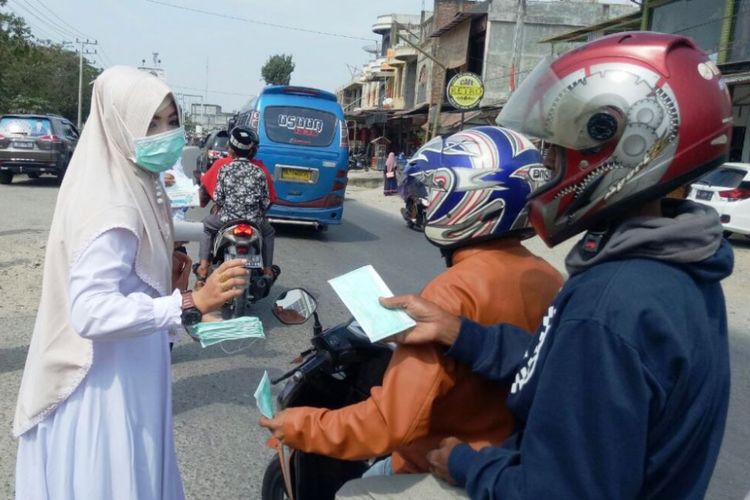 Petugas medis membagikan masker gratis pada pengguna jalan di Kota Lhoksukon, Kabupaten Aceh Utara, Selasa (20/2/2018).