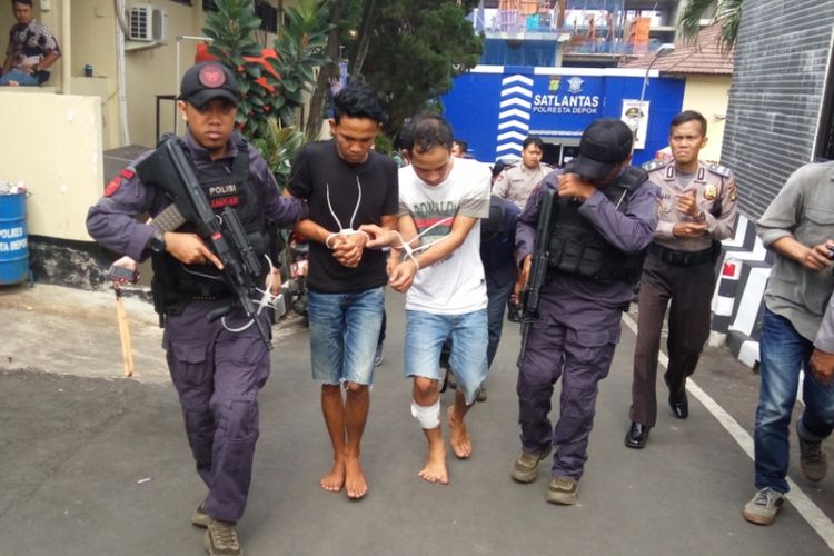 Dua orang anggota komplotan pencuri ATM saat ditangkap dan dibawa ke Mapolresta Depok pada Jumat (28/7/2017). Tampak salah seorang diantaranya berjalan pincang akibat kakinya ditembak oleh polisi.