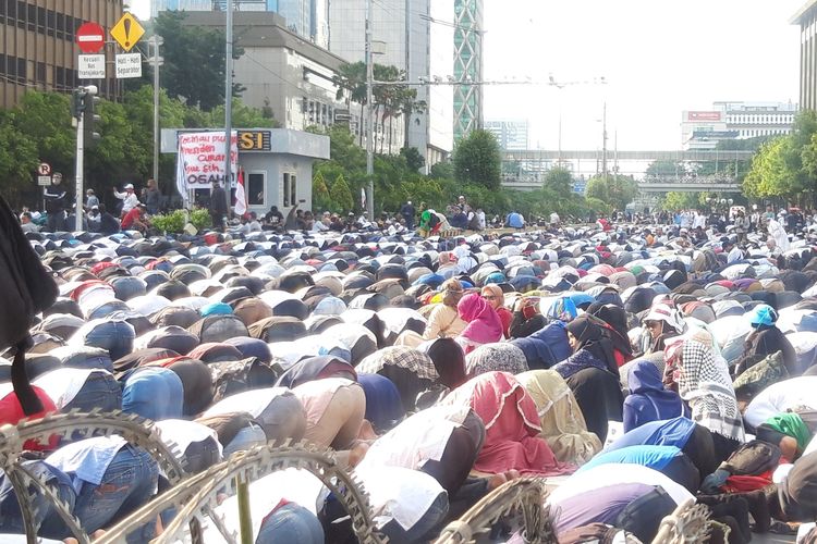 Peserta aksi unjuk rasa shalat di depan Bawaslu dengan beralaskan koran dan kardus, Rabu (22/5/2019)