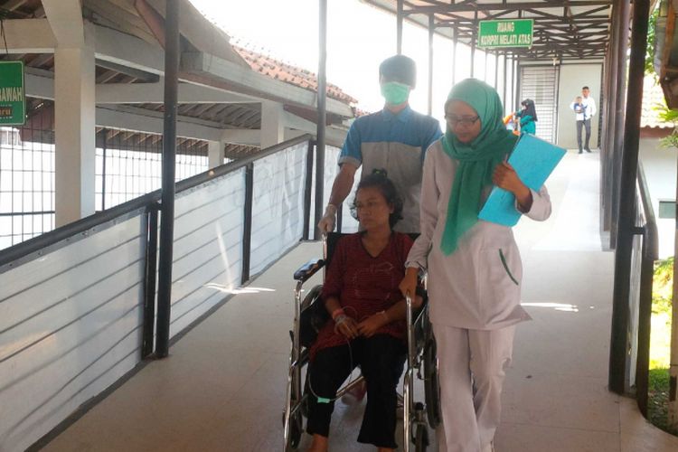 Pasien Nining Sunarsih (duduk di kursi roda) didampingi dua perawat saat dipindah ruangan di RSUD R Syamsudin,Kota Sukabumi, Jawa Barat, Rabu (4/7/2018).(KOMPAS.com/BUDIYANTO)