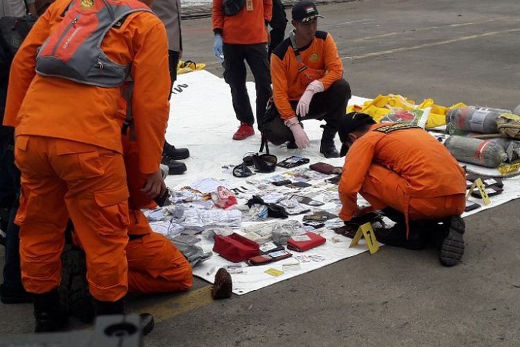 Petugas memeriksa puluhan kartu identitas yang diduha milik korban jatuhnya pesawat Lion Air JT 610 yang ditemukan dari perairan Karawang di Dermaga JICT 2 Pelabuhan Tanjung Priok, Selasa (30/10/2018).