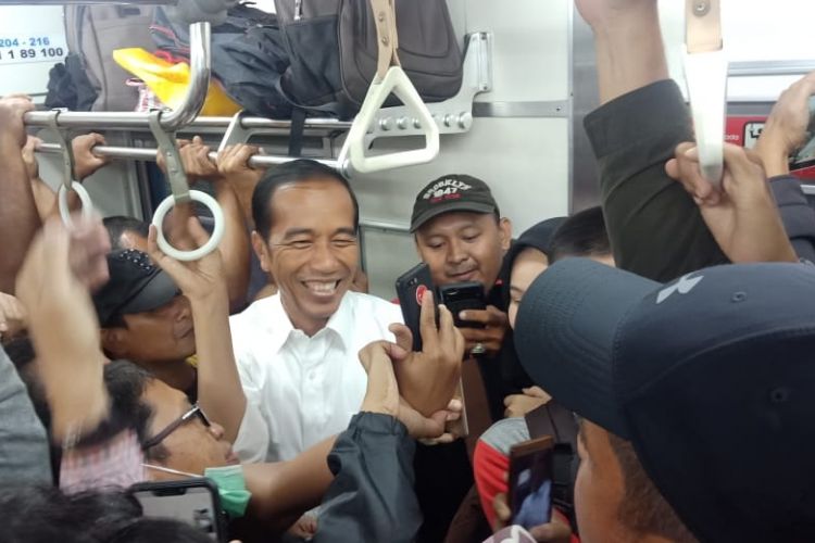 Penumpang KRL Commuterline jurusan Bogor berebut selfie bersama Presiden Jokowi di dalam gerbong kereta, Rabu (6/3/2019).