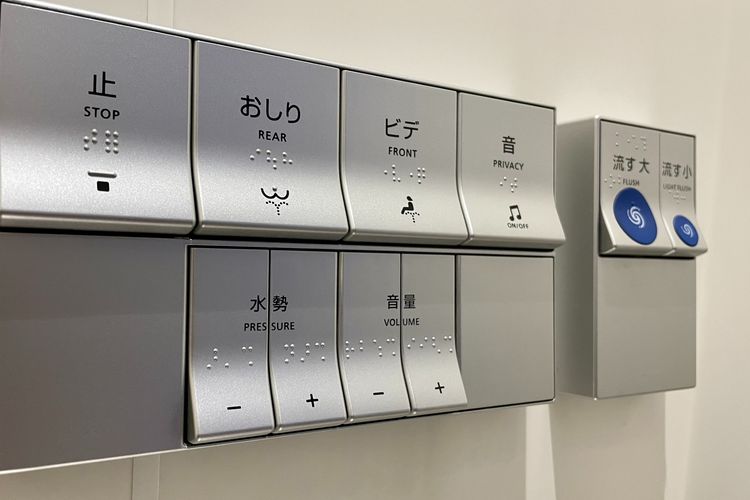 Tombol toilet canggih di Jepang di tembok. Lengkap dengan gambar, Bahasa Inggris, dan Bahasa Jepang.