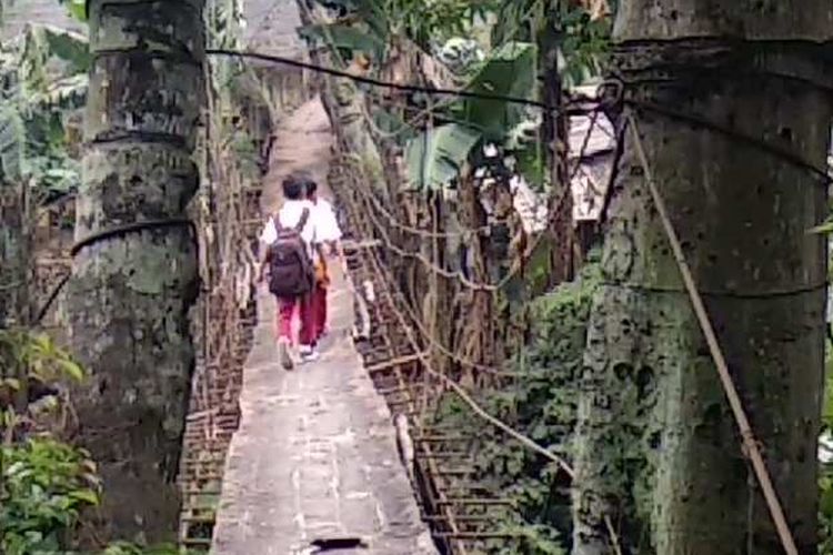 Anak-anak SDN 15 Srengseng Sawah, Jagakarsa, Jakarta Selatan, melintasi jembatan gantung untuk pulang ke Kelapa Dua, Depok, Jawa Barat, Senin (22/1/2018).