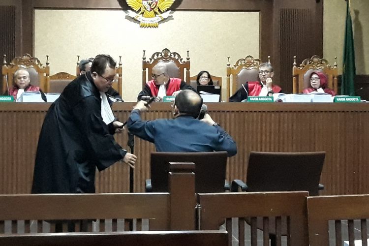 Anggota tim pengacara Fredrich Yunadi membantu memasangkan tiang penyangga mikrofon di Pengadilan Tipikor Jakarta, Jumat (22/6/2018).