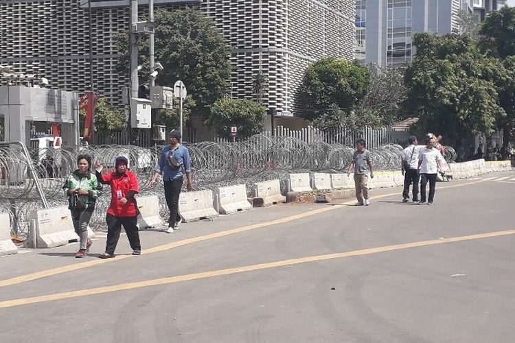 Pejalan kaki melintas di depan barikade kawat berduri yang dipasang di Jalan MH Thamrin depan Kantor Bawaslu RI, Jumat (24/5/2019).