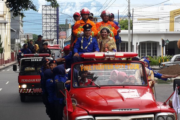 Pasangan pengantin Anggoro Setyo Pramono dan Novia Nur Eka Saputri saat diarak keliling Kota Malang menggunakan mobil pemadam kebakaran, Minggu (25/3/2018).