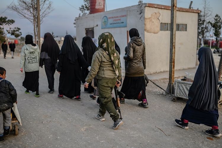 Para perempuan yang dikabarkana dalah para istri anggota ISIS berjalan di bawah pengawasan anggota perempuan Tentara Demokratik Suriah (SDF) di kamp al-Hol, provons Hasakeh, Suriah. 