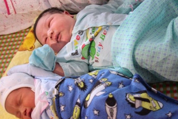 Tran Tien Quoc (atas) sedang tidur di samping bayi laki-laki. Tran Tien Quoc dinobatkan sebagai salah satu bayi terberat di Asia Tenggara
