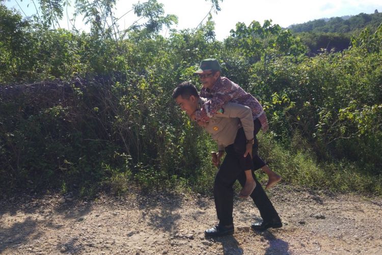 Seorang anggota Polres Buton menggendong kakek tua yamg kelelahan saat menuju ke kebunnya. Foto ini viral di media sosial.