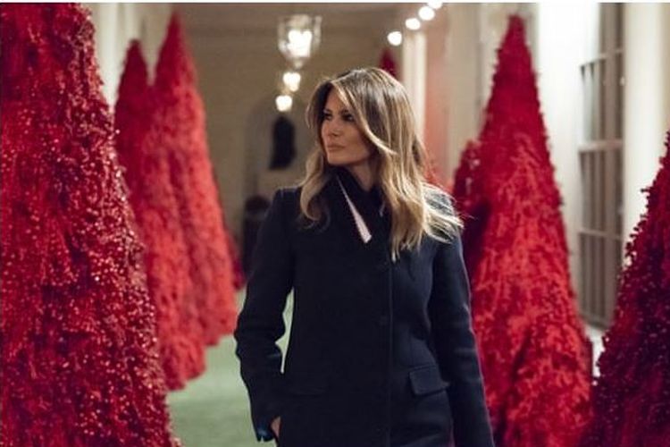 Melania berjalan di antara pohon natal merah hasil idenya di Gedung Putih.