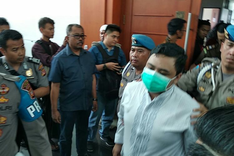 Tampak saksi korban MKU yang mengenakan masker hadir dalam pengawalan pihak kepolisian tiba di ruang sidang dugaan penganiayaan dengan terdakwa Bahar Bin Smith, Kamis (28/3/2019). 