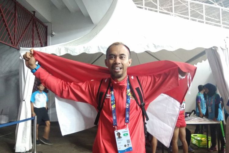 Atlet para-atletik Indonesia Settiyo Budi Hartanto berfoto sambil membawa Bendera Merah Putih seusai memastikan medali perak dari nomor lompat jauh T45/46/47 putra Asian Para Games 2018 di Stadion Utama Gelora Bung Karno, Senayan, Jakarta, Senin (8/10).