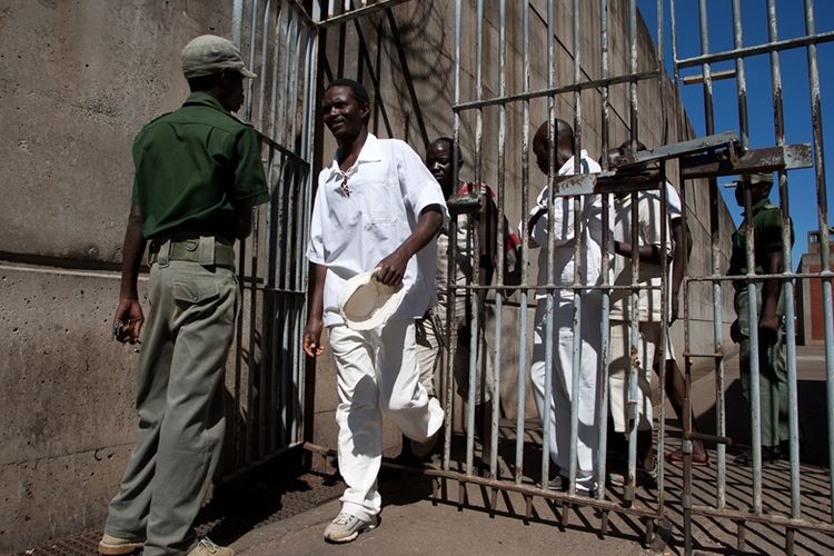 Dokumen foto memperlihatkan tahanan berjalan melewati penjaga di Penjara Keamanan Tinggi Chikurubi di Harare, Zimbabwe. Presiden Emmerson Mnangagwa mengampuni sekitar 3.000 tahanan guna mengurangi kepadatan populasi di dalam penjara.