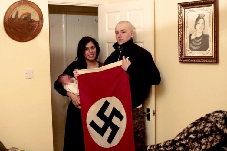 Pasangan Adam Thomas (22) dan kekasihnya Claudia Patatas (38) berfoto sambil membawa bendera Nazi dengan putra mereka yang diberi nama Adolf. Keduanya dituduh sebagai anggota kelompok sayap kanan terlarang Aksi Nasional.